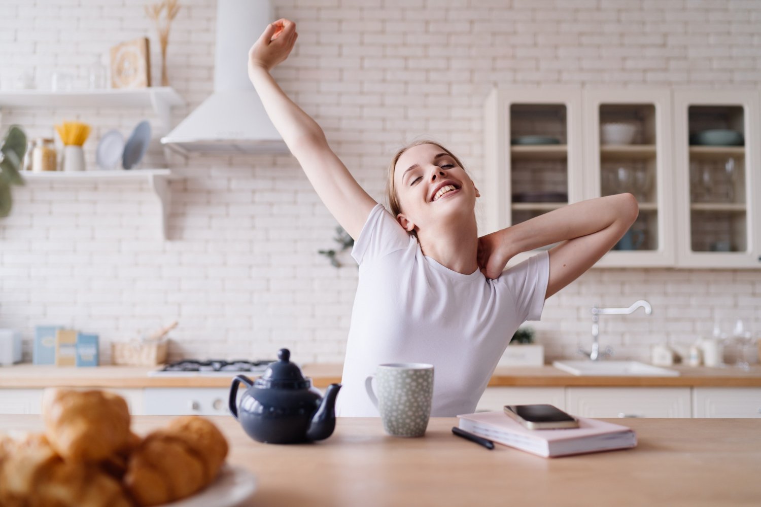 Woman stretching with morning sunlight streaming through window as part of her simple morning routines.