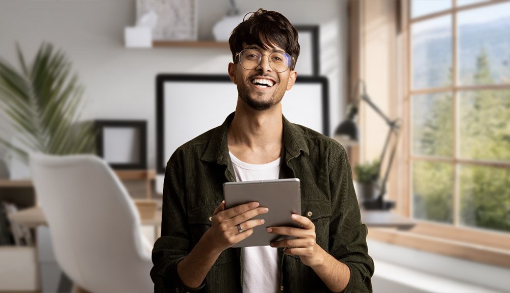 Happy spectacled young man looking at the best freelance websites on his device.
